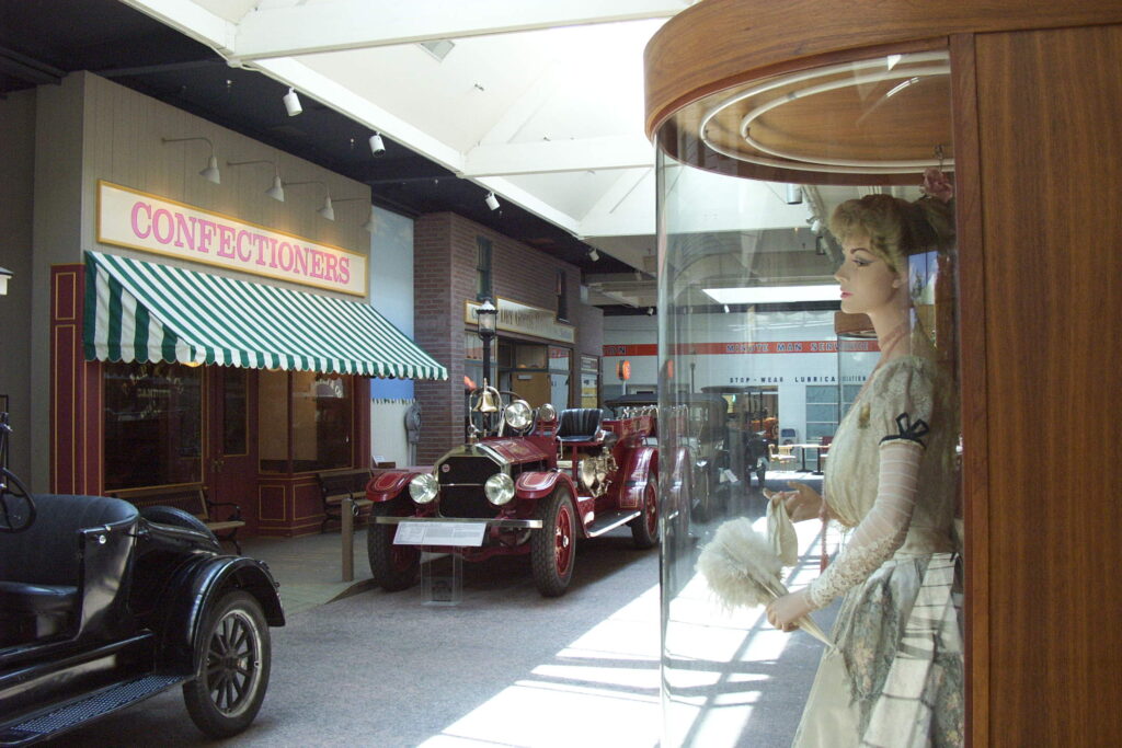 False storefronts and costumed mannequins line the “streets” within the Reno automobile museum.